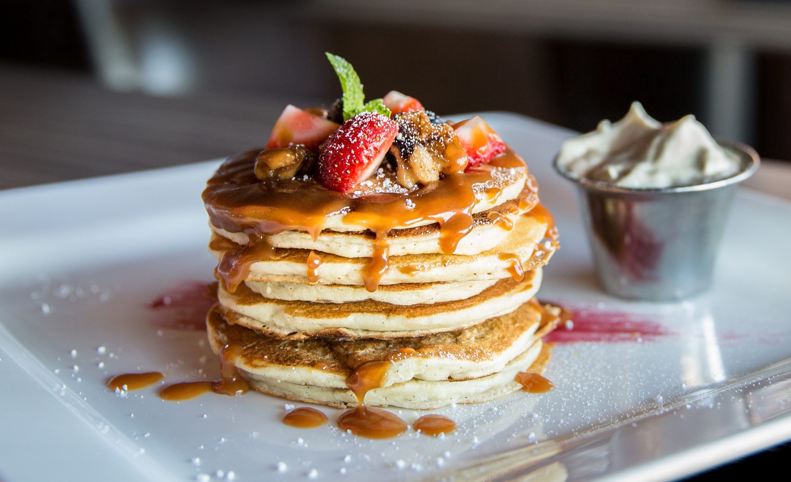 A stack of pancakes topped with berries and syrup.