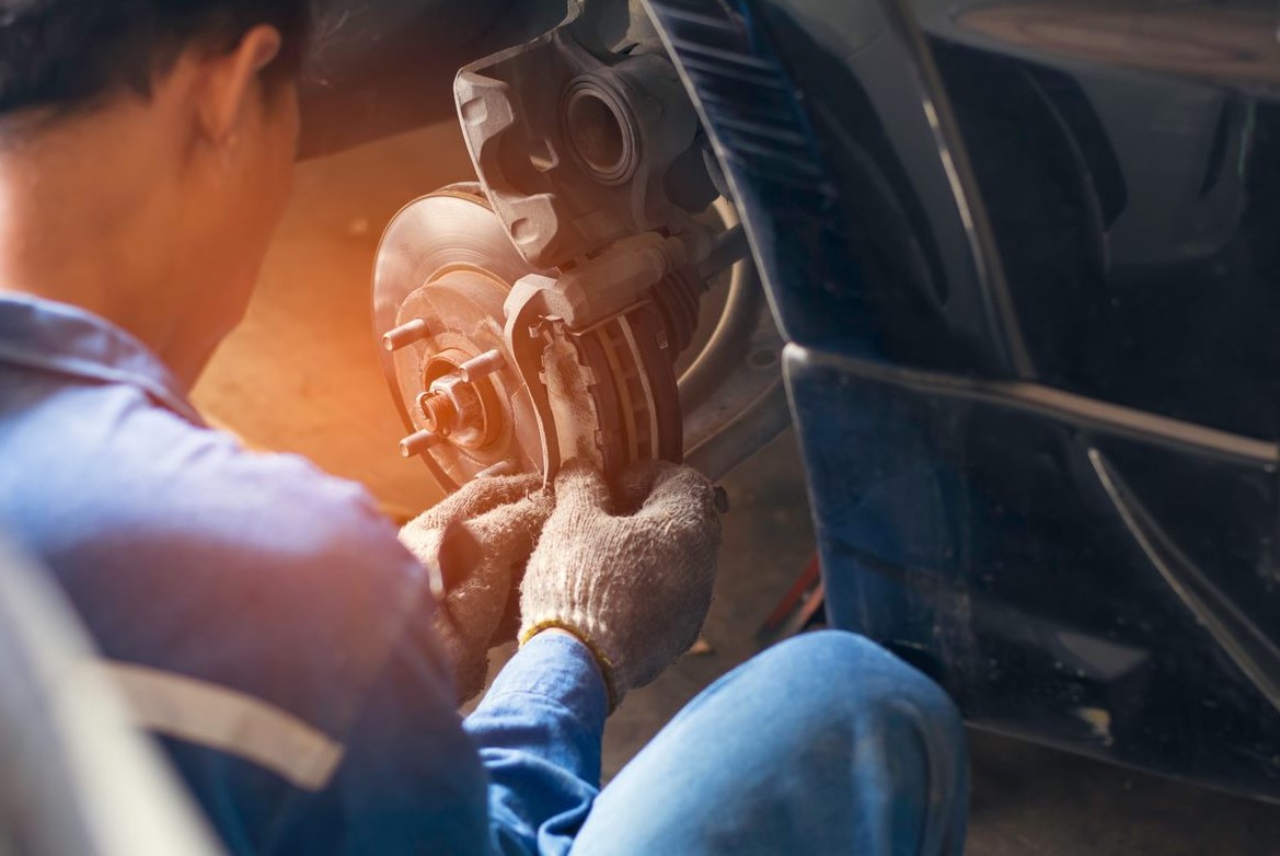 A mechanic in a blue jumpsuit repairing brakes.